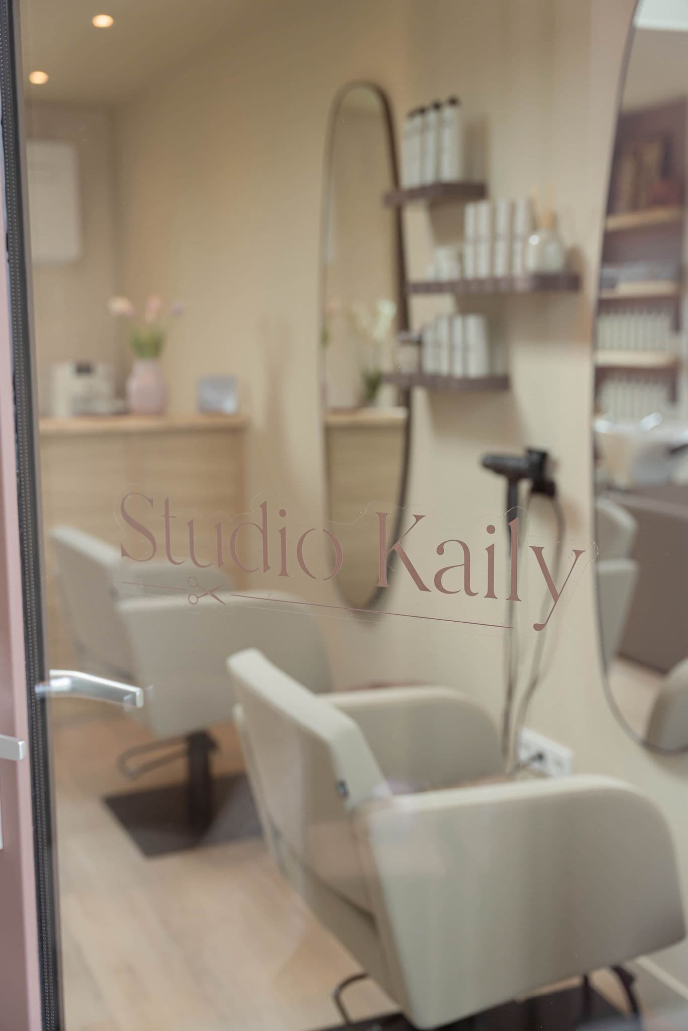 Kapstoelen weerspiegeld in de glazen deur van Studio Kaily